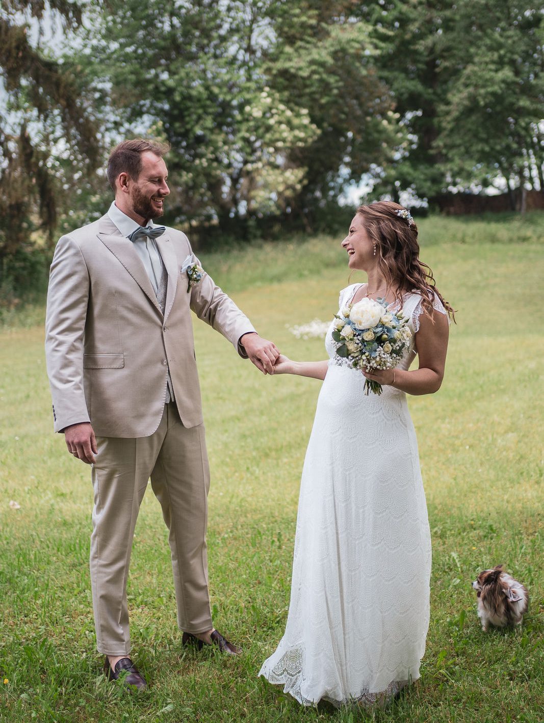 Hochzeit Wolfratshausen, Geretsried, Bad Tölz, Starnberg, Penzberg, Seeshaupt, München Brautpaar tanzt über die grüne Wiese, sie blicken sich lachend an, ihr kleiner Hund begleitet sie überall hin