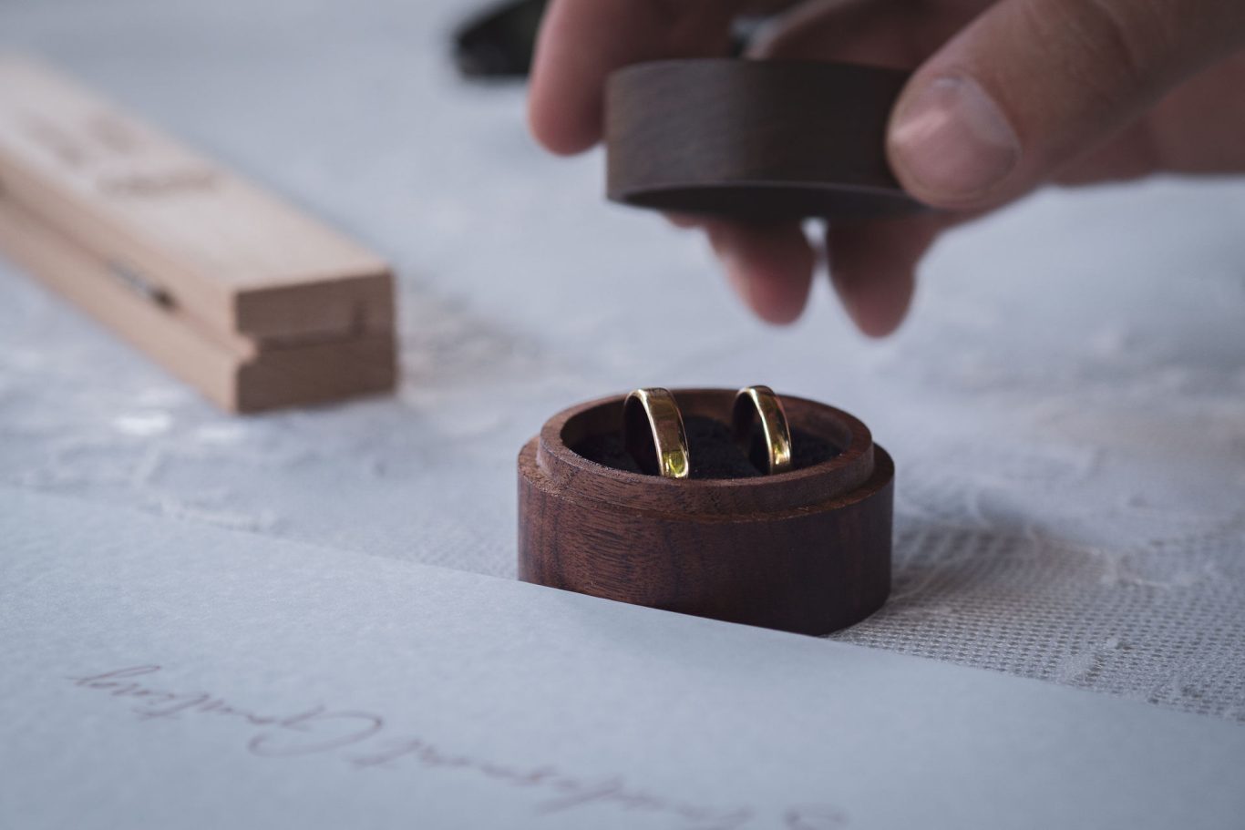 Hochzeit Detailaufnahme der Eheringe in einer kleinen Holzbox, von welcher jemand soeben den Deckel abhebt