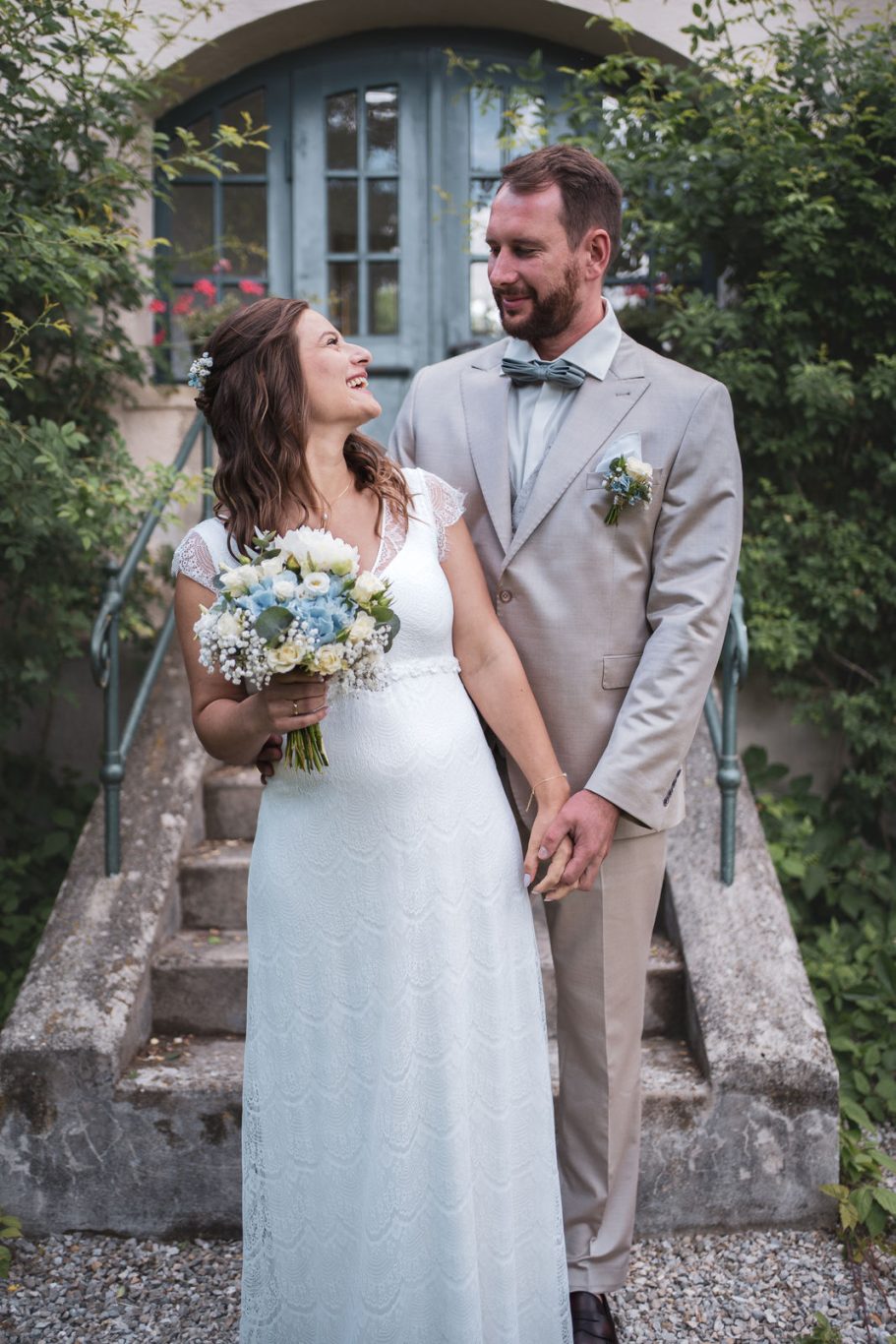 Hochzeit Ein festlich gekleidetes Brautpaar steht versetzt nebeneinander und blickt einander glücklich an