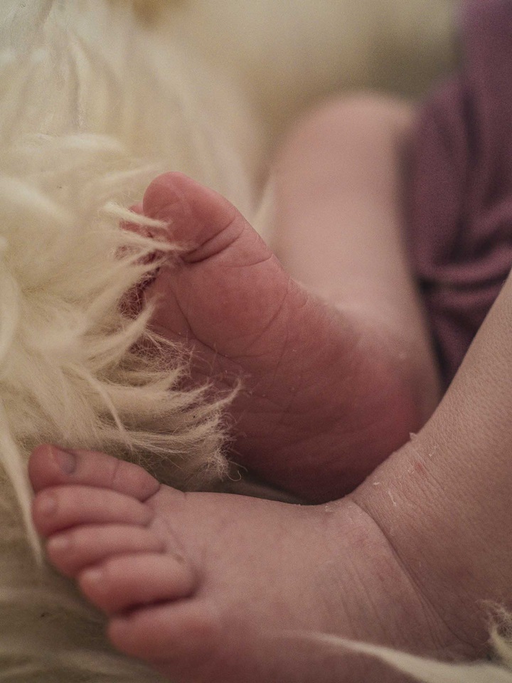 Detailaufnahme zweier kleiner Babyfüße auf weichem, hellen Schafsfell. Newbornshooting in und um Geretsried Bad-Tölz Wolfratshausen