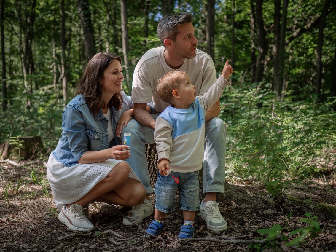 Eine Familie mit einem kleinen Kind im Wald, das auf etwas zeigt. Familienshooting in und um Geretsried Bad-Tölz Wolfratshausen