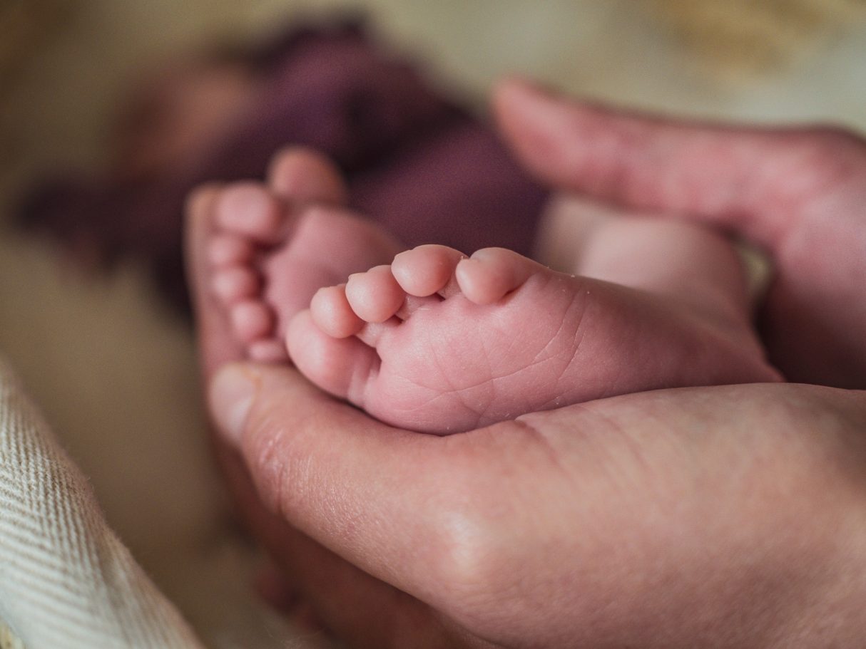 Detailaufnahme zweier zarter Babyfüße, die in einer Hand gehalten werden. Newbornshooting in und um Geretsried Bad-Tölz Wolfratshausen